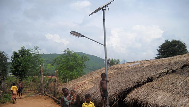 Solar street lights powering rural off-grid road near thatched homes