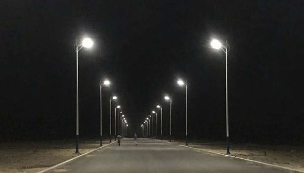 Solar street lights lining wide road at night with pedestrians - reliable 8-16 hours of continuous lighting per full charge