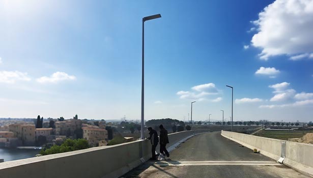 Commercial solar street lights installed along a bridge on a sunny day, showcasing their versatile installation and winter-ready performance across different climates