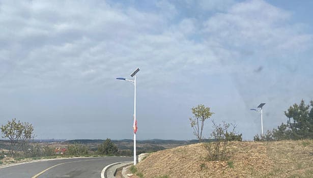 Commercial solar street light installed on a rural road, with hills and sparse vegetation in the background