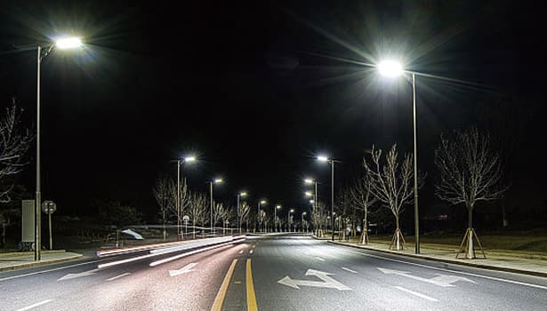 Solar street lights illuminating an urban road at night.