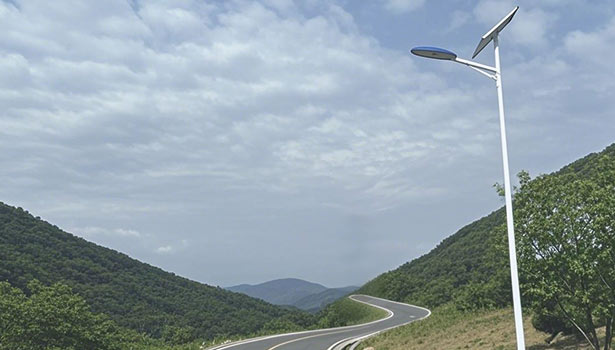 Solar street light installed on the mountain road, surrounded by mountains and winding road