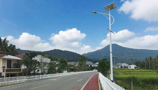 Solar street light beside a rural way with houses and mountains, representing solar street lights for diverse highway environments