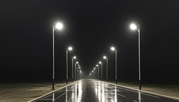 Solar street lights illuminating a wet road at night, showcasing lighting performance in rainy conditions