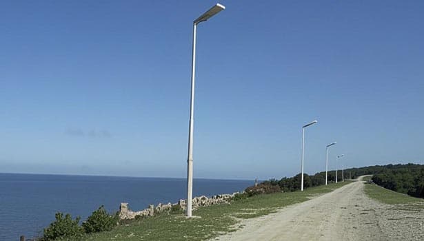 Solar street lights installed along a coastal road under a clear blue sky during the day