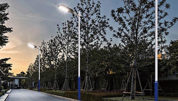 Solar-powered street lights line a tree-lined community path, enhancing eco-friendly outdoor lighting for pedestrians.