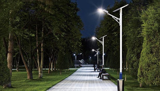 Solar street lights on park shaded pathway with people relaxing