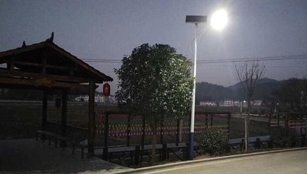 Solar street light glowing brightly at night in a rural area