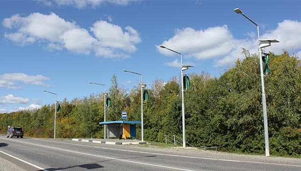 Multiple solar street lights installed along roadside under blue sky