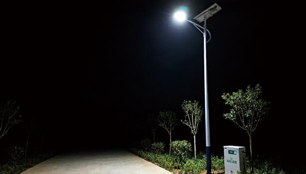 Solar street light for natural areas installed along rural path at night, off-grid lighting solution