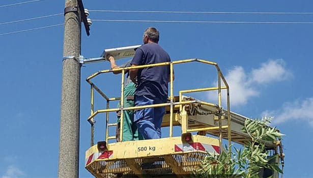 Electricians on a lift repairing street light wiring, demonstrating professional installation and maintenance.