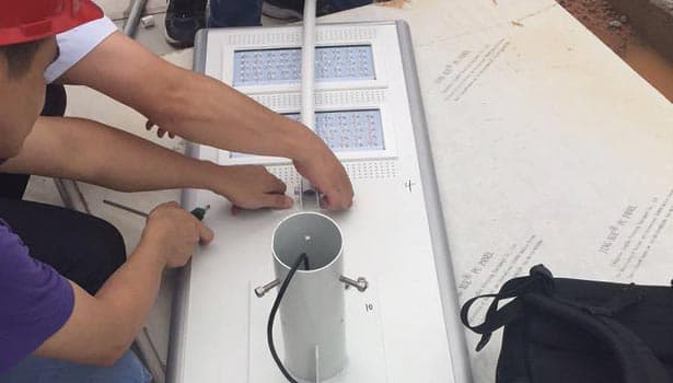 Technicians connecting wires to solar street light pole, focusing on proper wiring techniques and polarity.