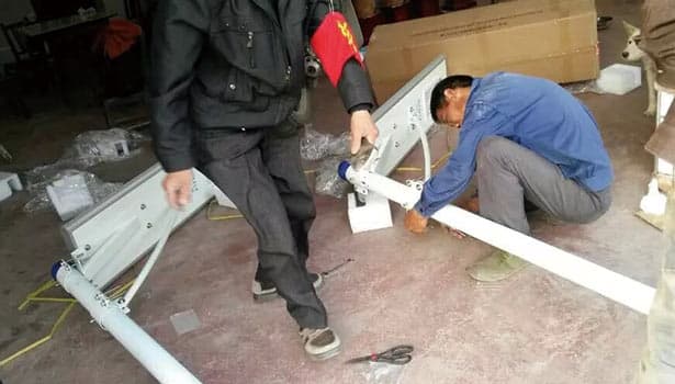 Workers assembling solar street light components and wiring, showing the installation process step by step.