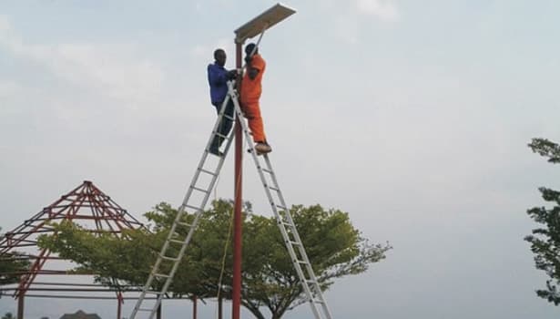 Two workers installing solar panel on street light pole, demonstrating professional solar street light installation process.